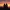 Two people sitting together on a rock, watching a warm sunset over distant mountains