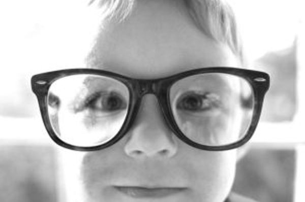 Close-up of a face wearing oversized glasses in black and white