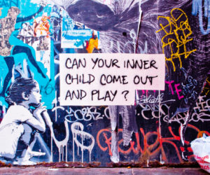 Graffiti-covered wall with a sign asking if your inner child can come out and play