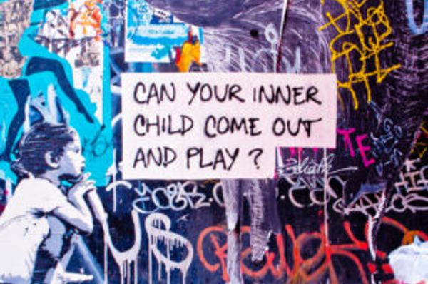 Graffiti-covered wall with a sign asking if your inner child can come out and play