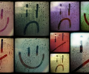 Smiling and frowning faces drawn on several fogged glass panes