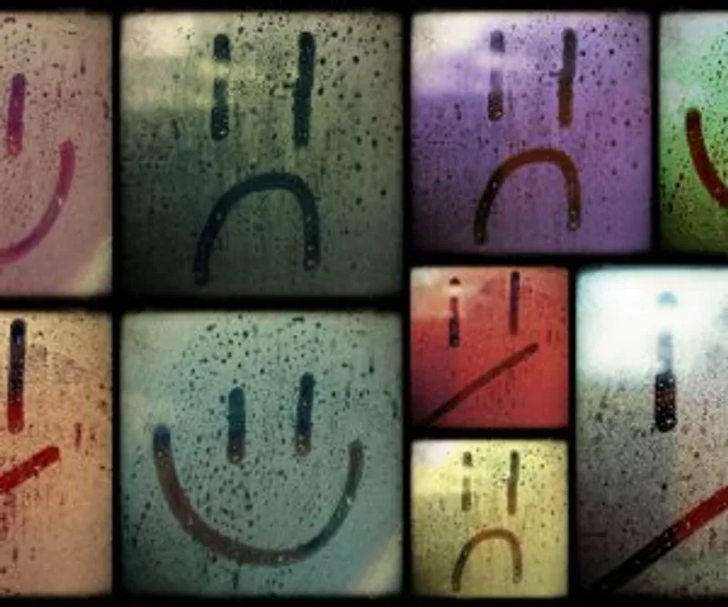 Smiling and frowning faces drawn on several fogged glass panes