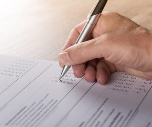 Close-up of a hand using a pen to complete a printed form