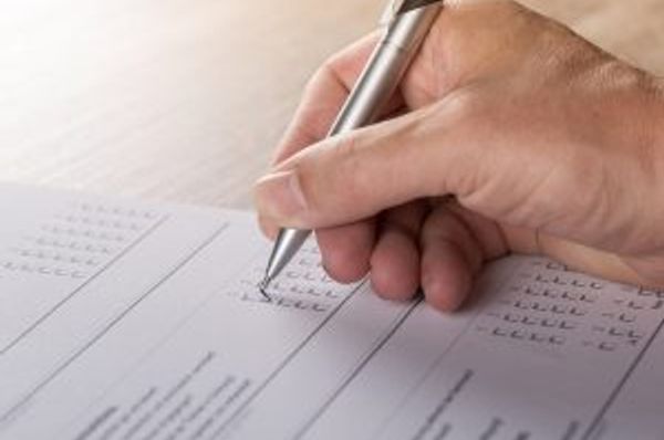Close-up of a hand using a pen to complete a printed form