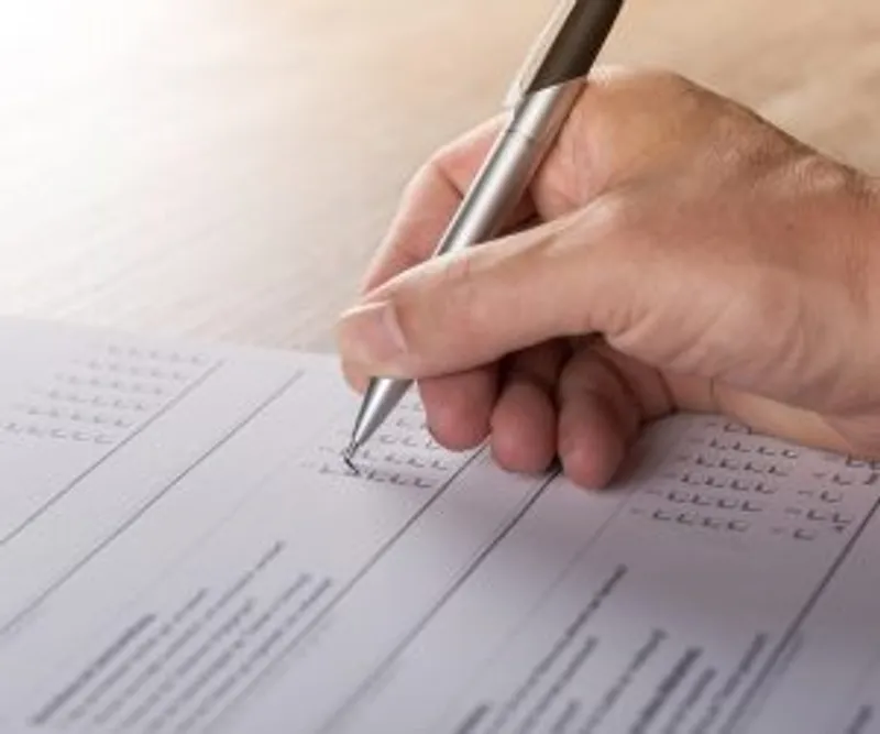 Close-up of a hand using a pen to complete a printed form