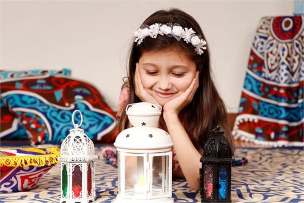 A child rests their chin in their hands while looking at three decorative lanterns