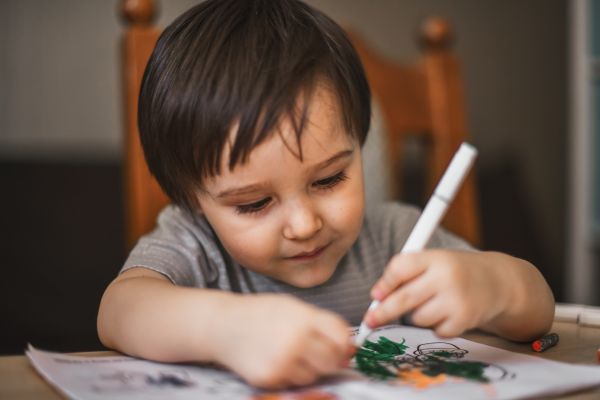 Child drawing on paper with a marker at a table