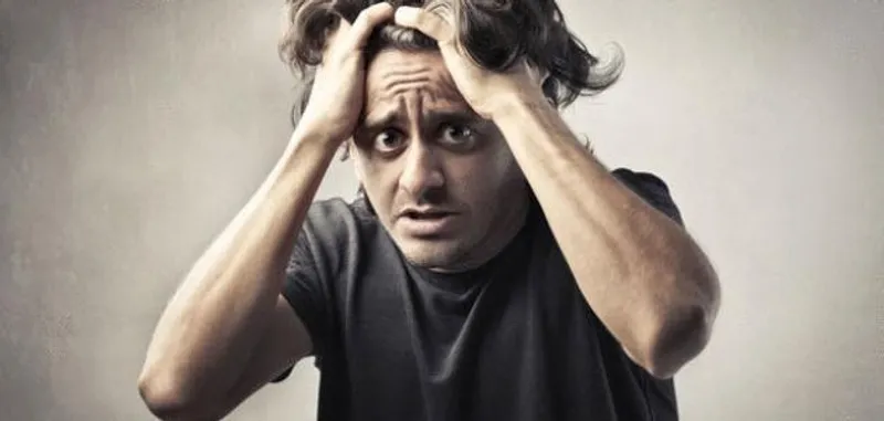 Person grips their hair with both hands and looks ahead with wide eyes