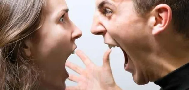Two people face each other at close range with open mouths and a raised hand