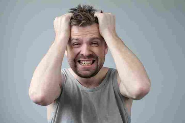 Person grips their hair with both hands while baring their teeth