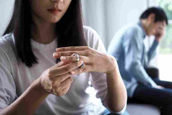 Person removes a ring while another sits blurred in the background