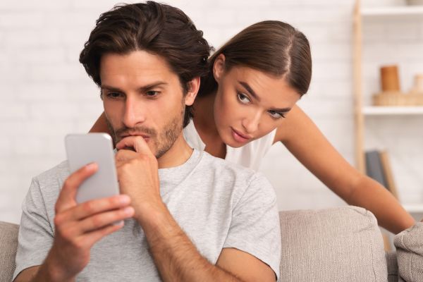 One person looks at a phone while another leans over their shoulder