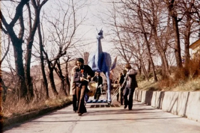 People walk beside a tall blue horse sculpture on a wooded path