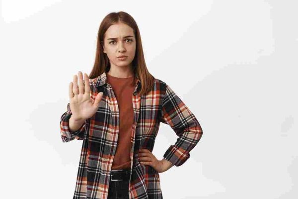 Person raises an open palm toward the viewer against a plain background