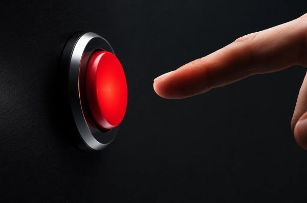 Finger hovering over a glowing red button in a dark, minimal scene, capturing tension.