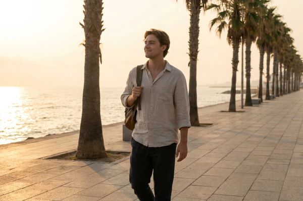 a young man walking along the corniche with calm expression and open posture