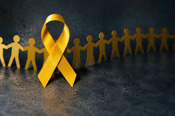 Golden awareness ribbon with linked paper figures symbolizing unity and support