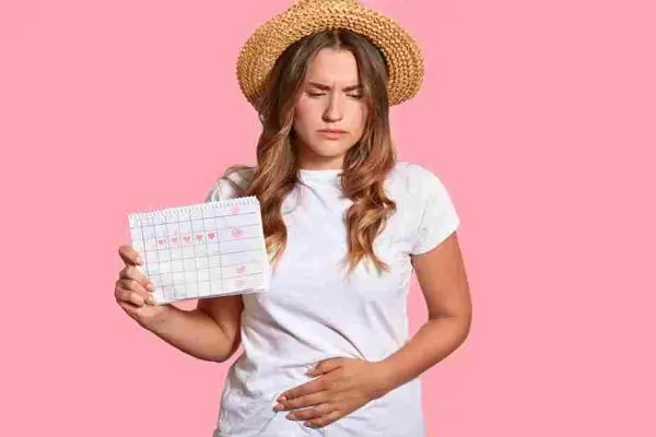 Person holds a calendar while pressing one hand against their lower abdomen