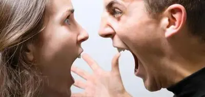 Two people face each other at close range with open mouths and a raised hand