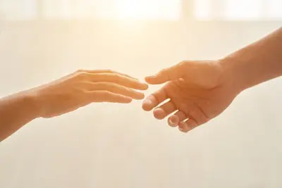 Two hands reach toward each other in soft light