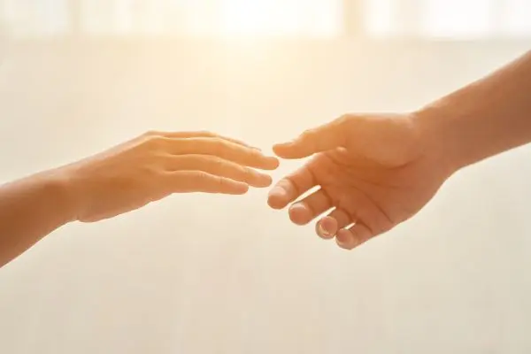 Two hands reach toward each other in soft light