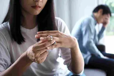 Person removes a ring while another sits blurred in the background