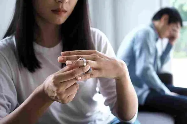 Person removes a ring while another sits blurred in the background