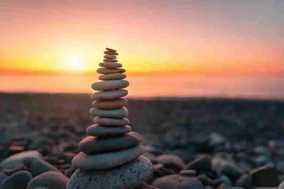 Smooth stones stacked on a rocky beach at sunset