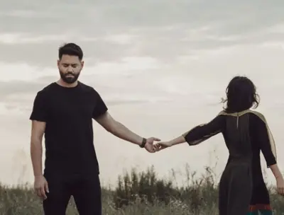 Two people standing apart and touching fingertips in an open field