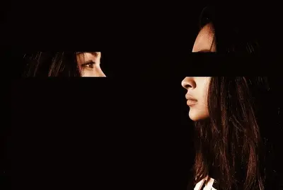 Two faces appear through narrow openings in a dark composition