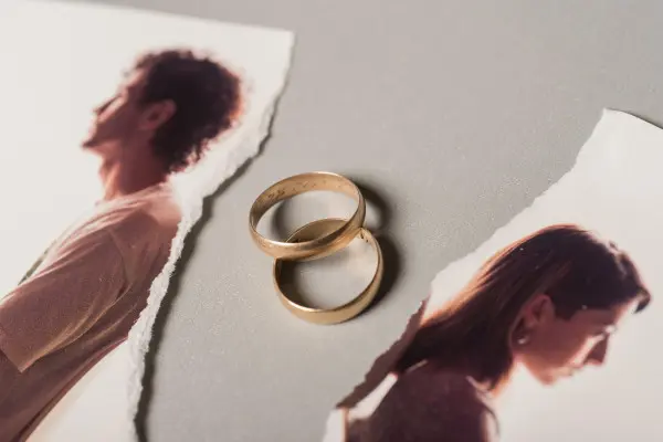 Two gold rings lie between torn portraits of two people