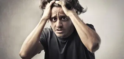 Person grips their hair with both hands while looking upward