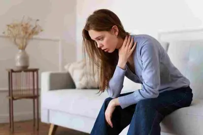 Seated adult leans forward with one hand resting on the neck
