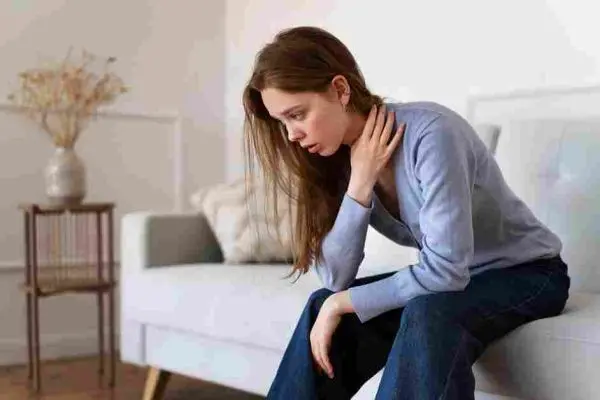 Seated adult leans forward with one hand resting on the neck