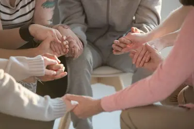 People seated in a circle holding hands