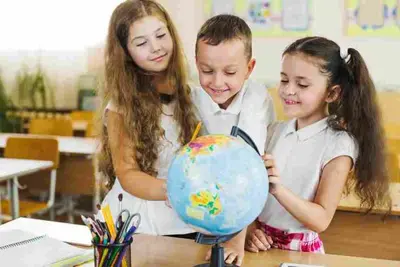 Three children gather around a globe in a classroom