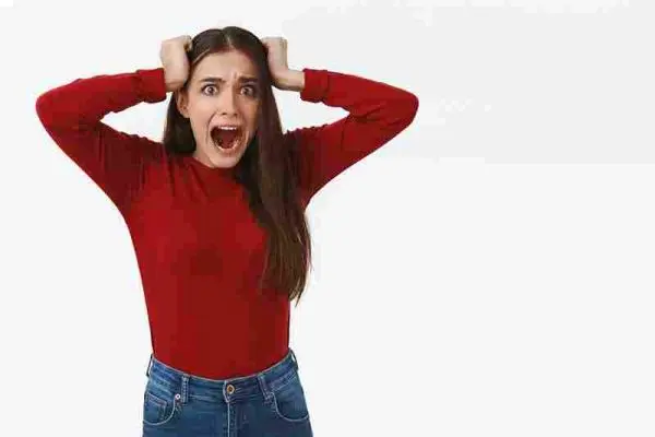 Person holds both sides of their head with their mouth open