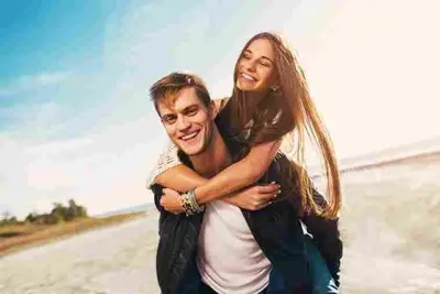 Two smiling adults share a piggyback ride outdoors