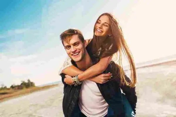 Two smiling adults share a piggyback ride outdoors