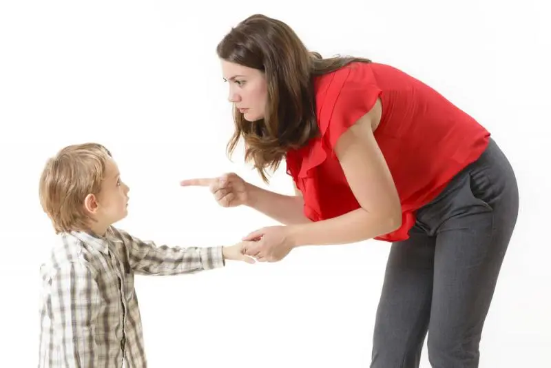 Adult points toward a child while holding the child's hand